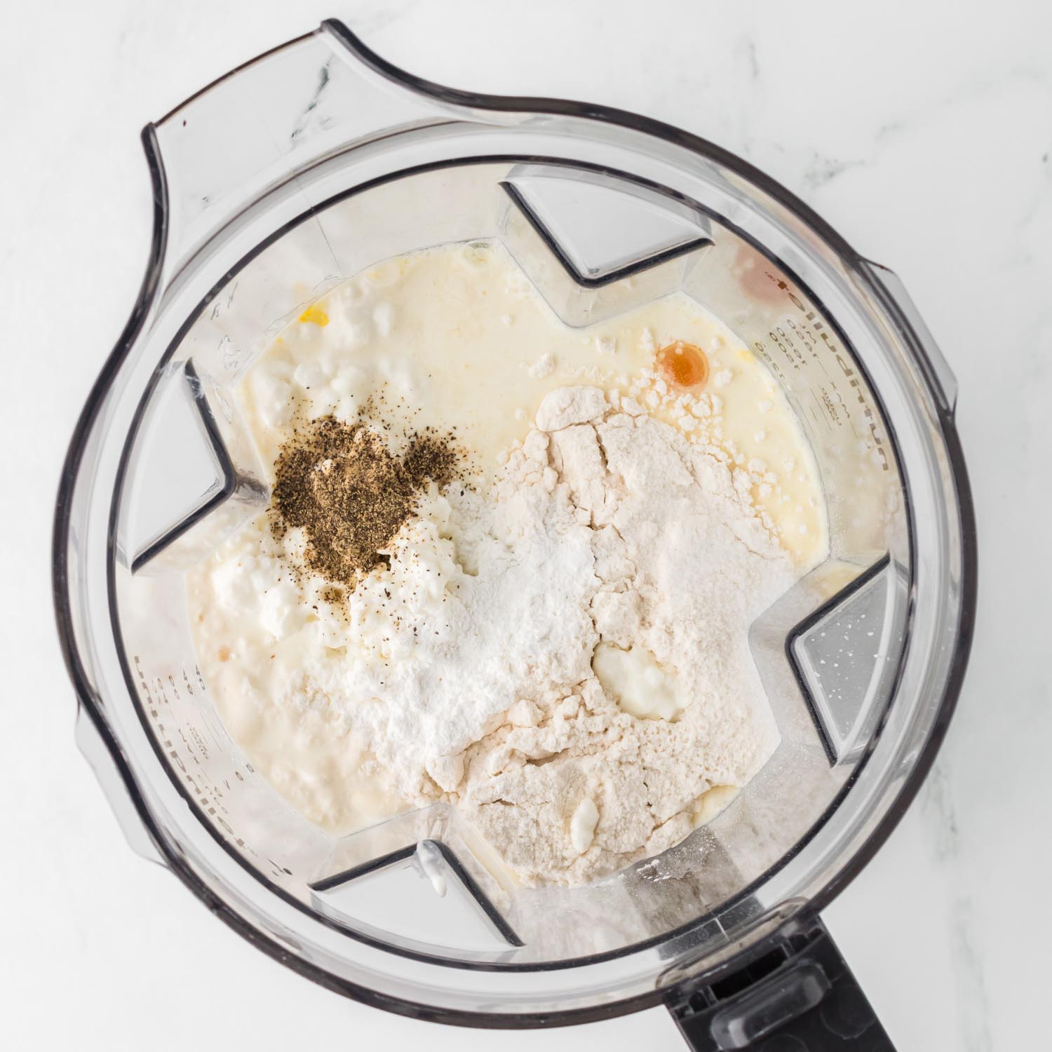 eggs in a blender with flour, cream, cottage cheese, and seasonings.