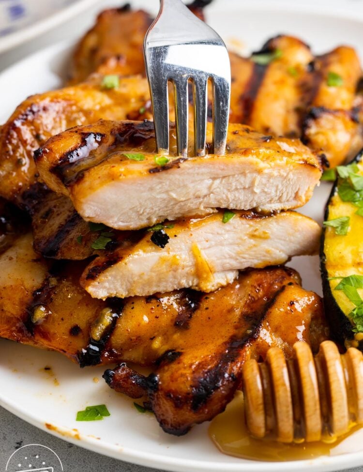 grilled honey mustard chicken on a plate. A piece has been cut in half to show the juicy interior.