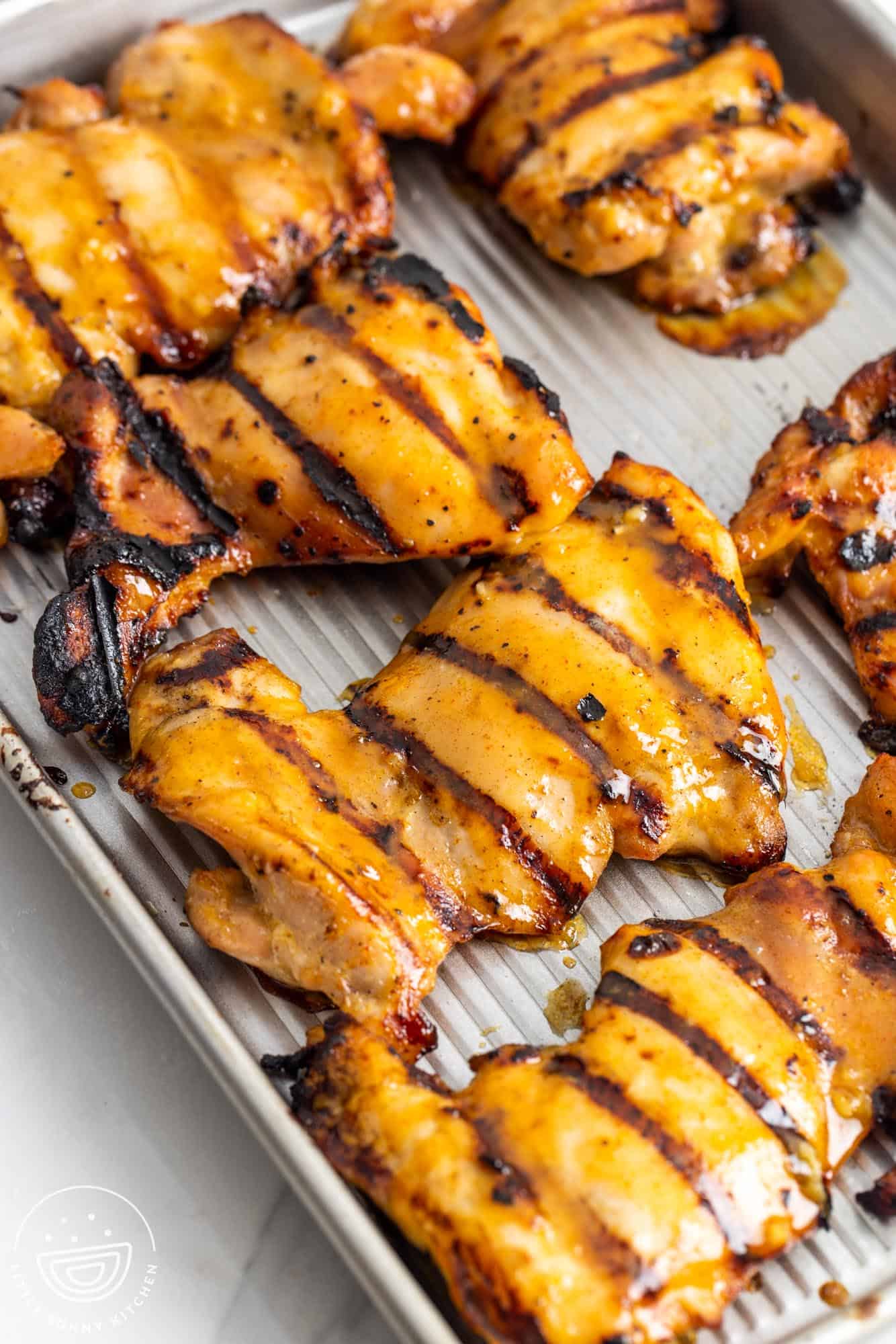 grilled chicken thighs with honey mustard glaze on a sheet pan.