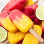 Close up shot of stacked mango raspberry popsicles on a white plate