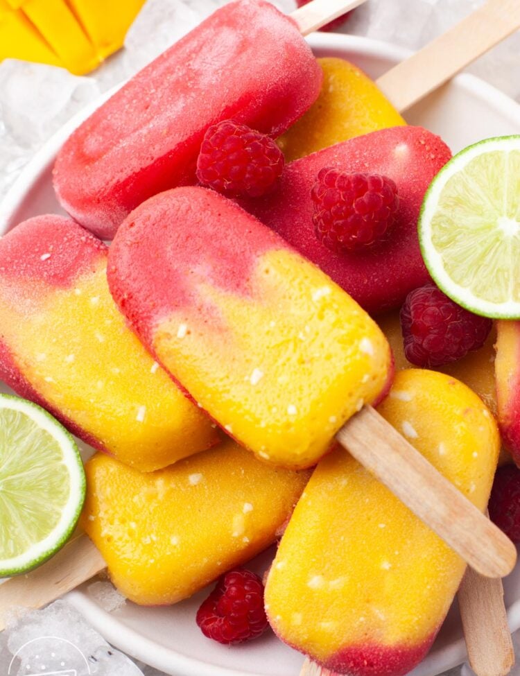Close up shot of stacked mango raspberry popsicles on a white plate