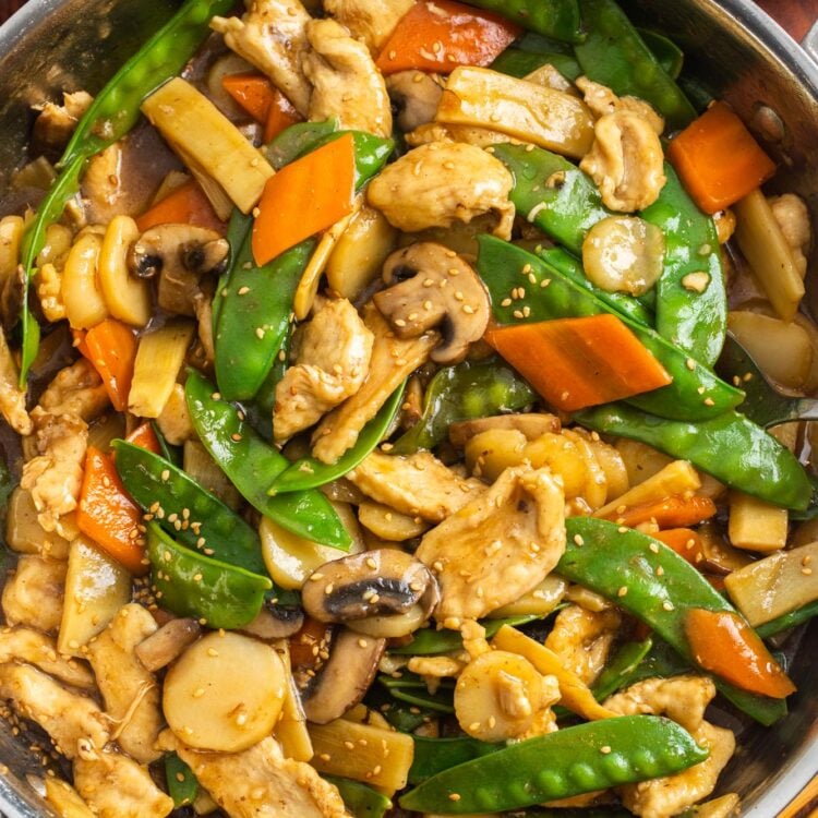 a large saute pan filled with homemade chinese food with chicken, mushrooms, and other veggies.