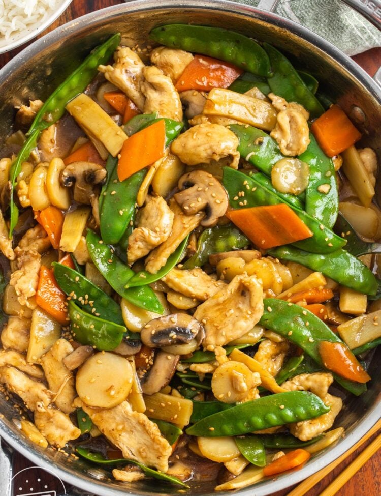 a large saute pan filled with homemade chinese food with chicken, mushrooms, and other veggies.