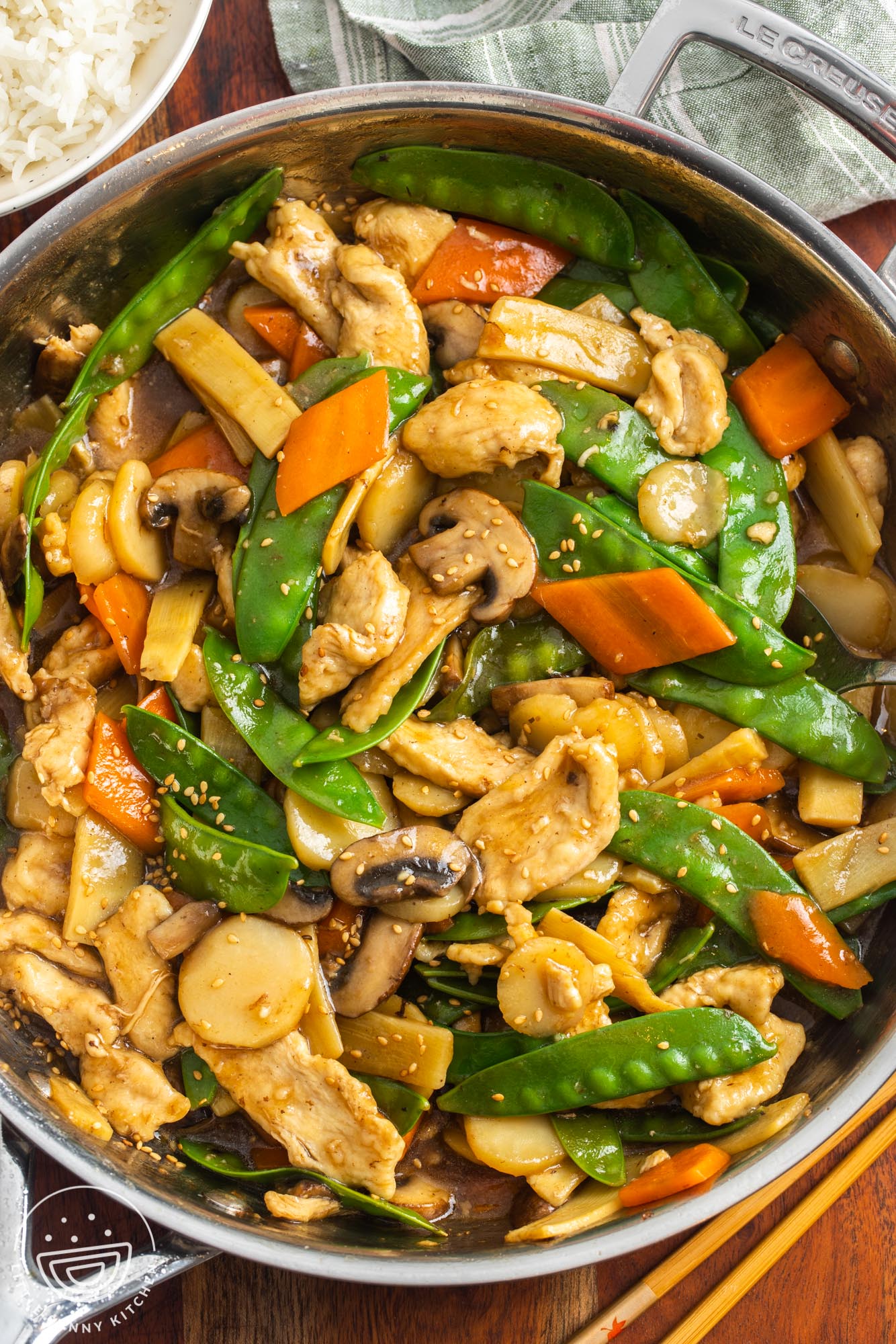 a large saute pan filled with homemade chinese food with chicken, mushrooms, and other veggies.