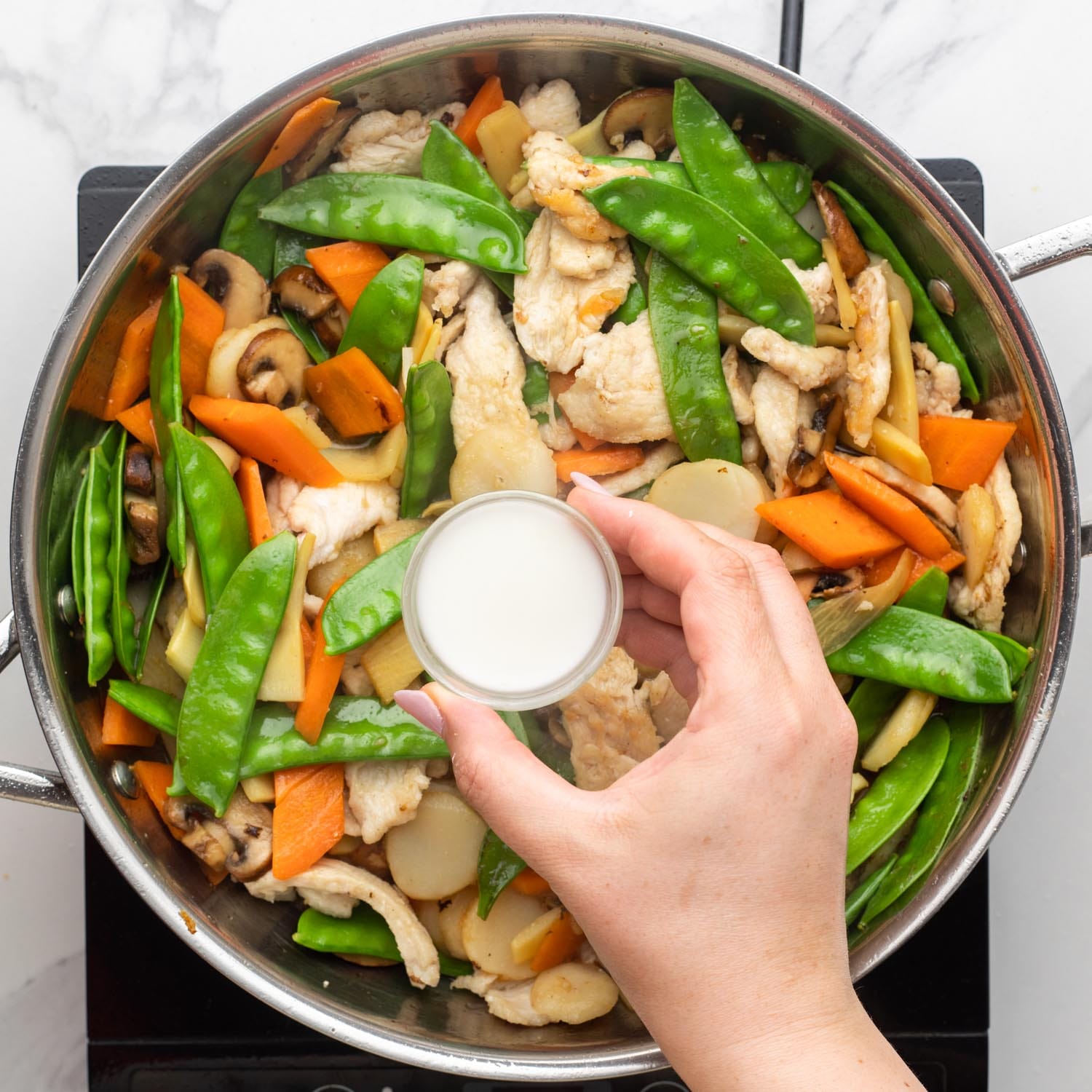 corn starch slurry added to homemade moo goo gai pan in a metal pan.