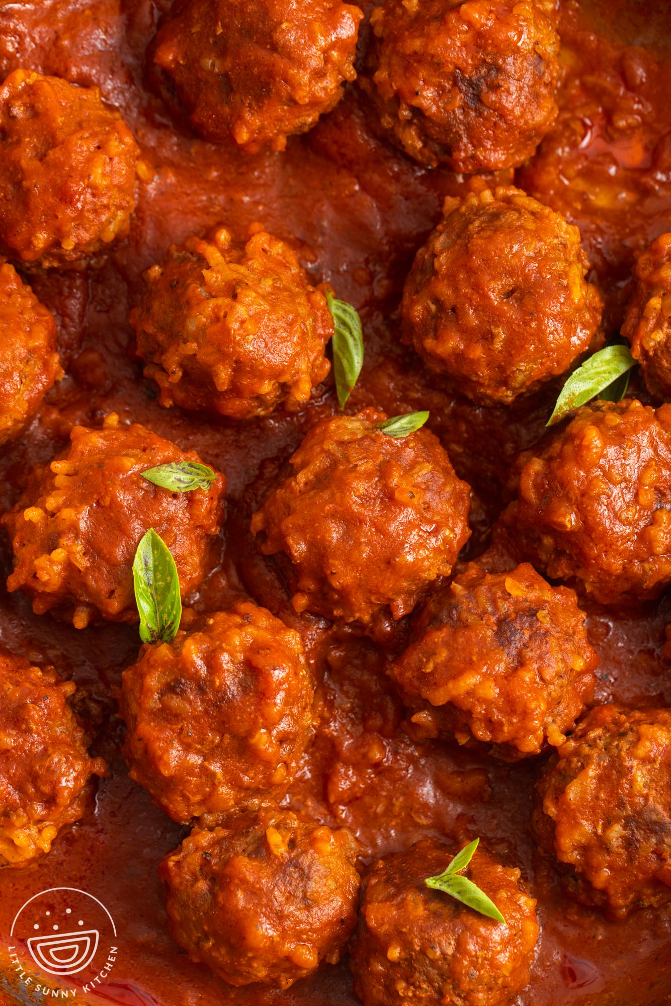 porcupine meatballs made with rice, in tomato sauce, garnished with small basil leaves.