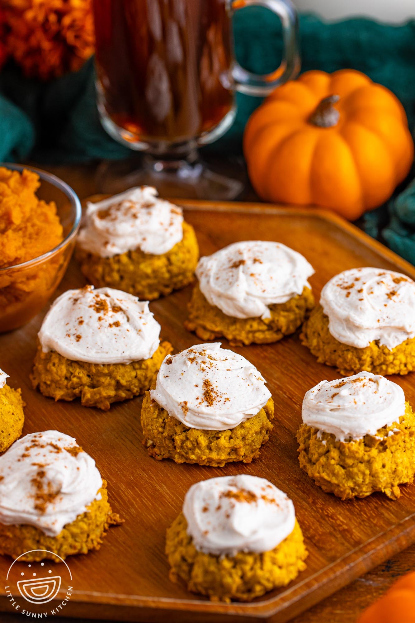 a wooden platter holding 9 thick pumpkin oatmeal cookies topped with pumpkin spice buttercream.