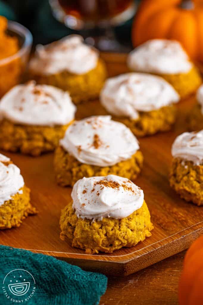 Closeup of pumpkin oatmeal cookies on a wooden tray. The cookies are frosted and sprinkled with pumpkin spice.