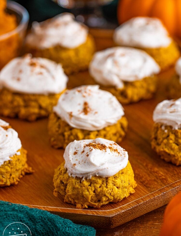 Closeup of pumpkin oatmeal cookies on a wooden tray. The cookies are frosted and sprinkled with pumpkin spice.