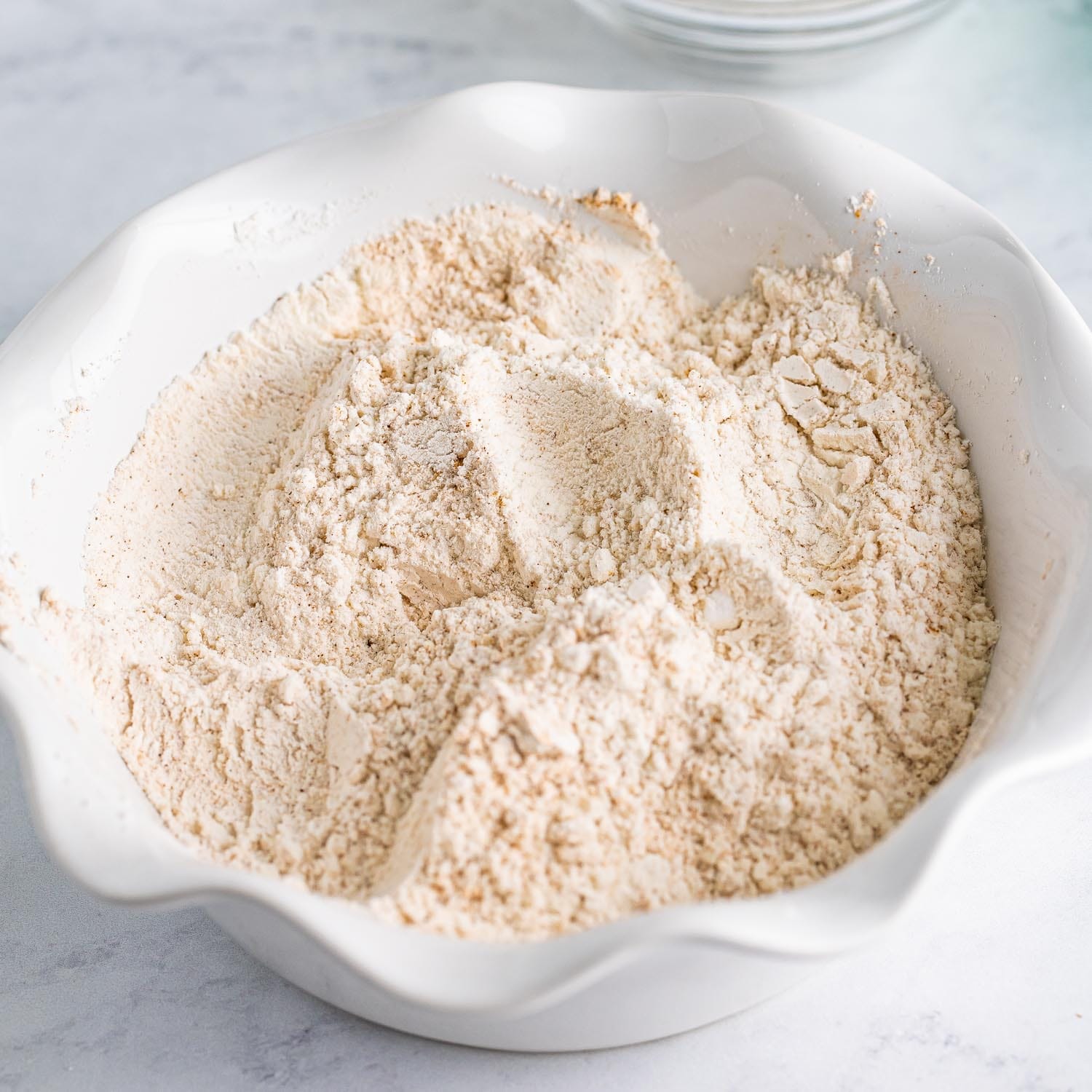 Flour mixed with spices in a fluted white bowl.