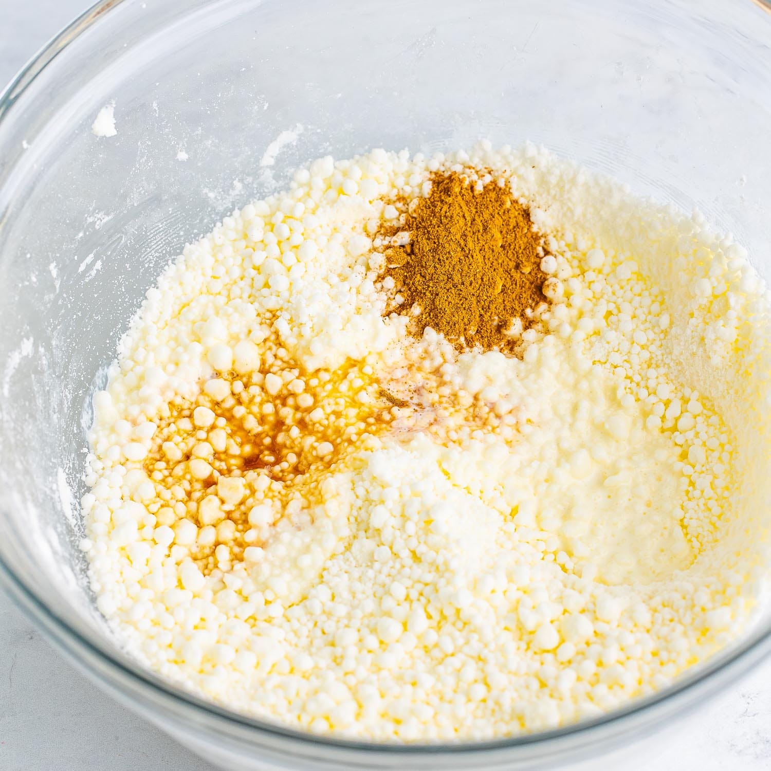 a glass bowl holding butter mixed with powdered sugar. Pumpkin spice and vanilla are added.