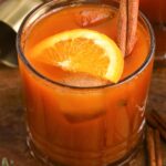 Pumpkin old fashioned cocktail in a glass, with a slice of orange and a cinnamon stick
