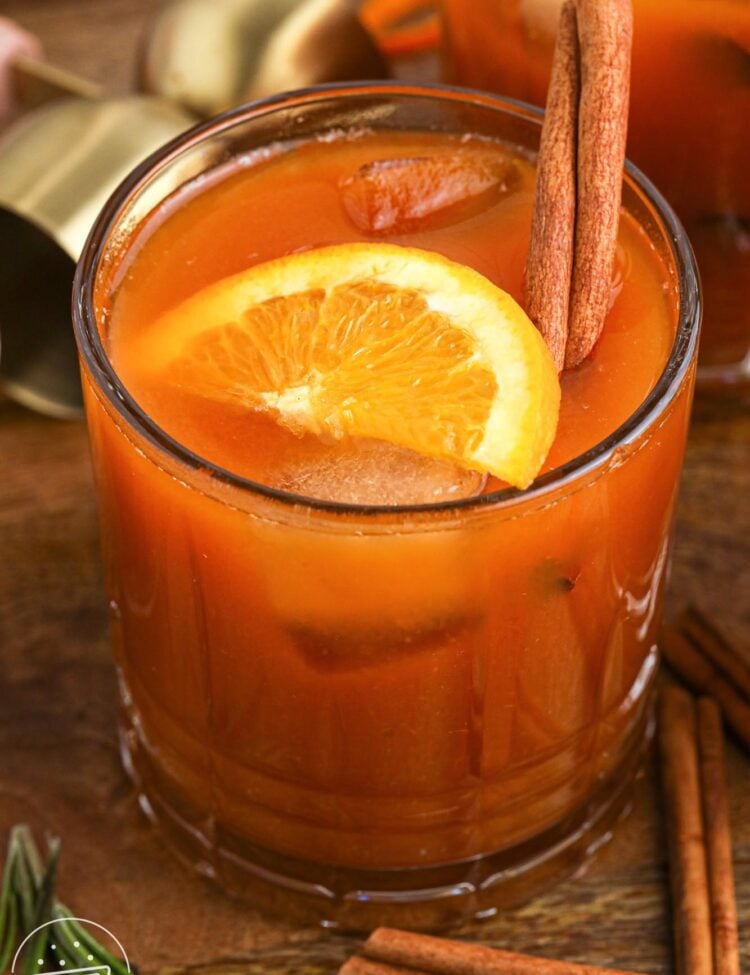 Pumpkin old fashioned cocktail in a glass, with a slice of orange and a cinnamon stick