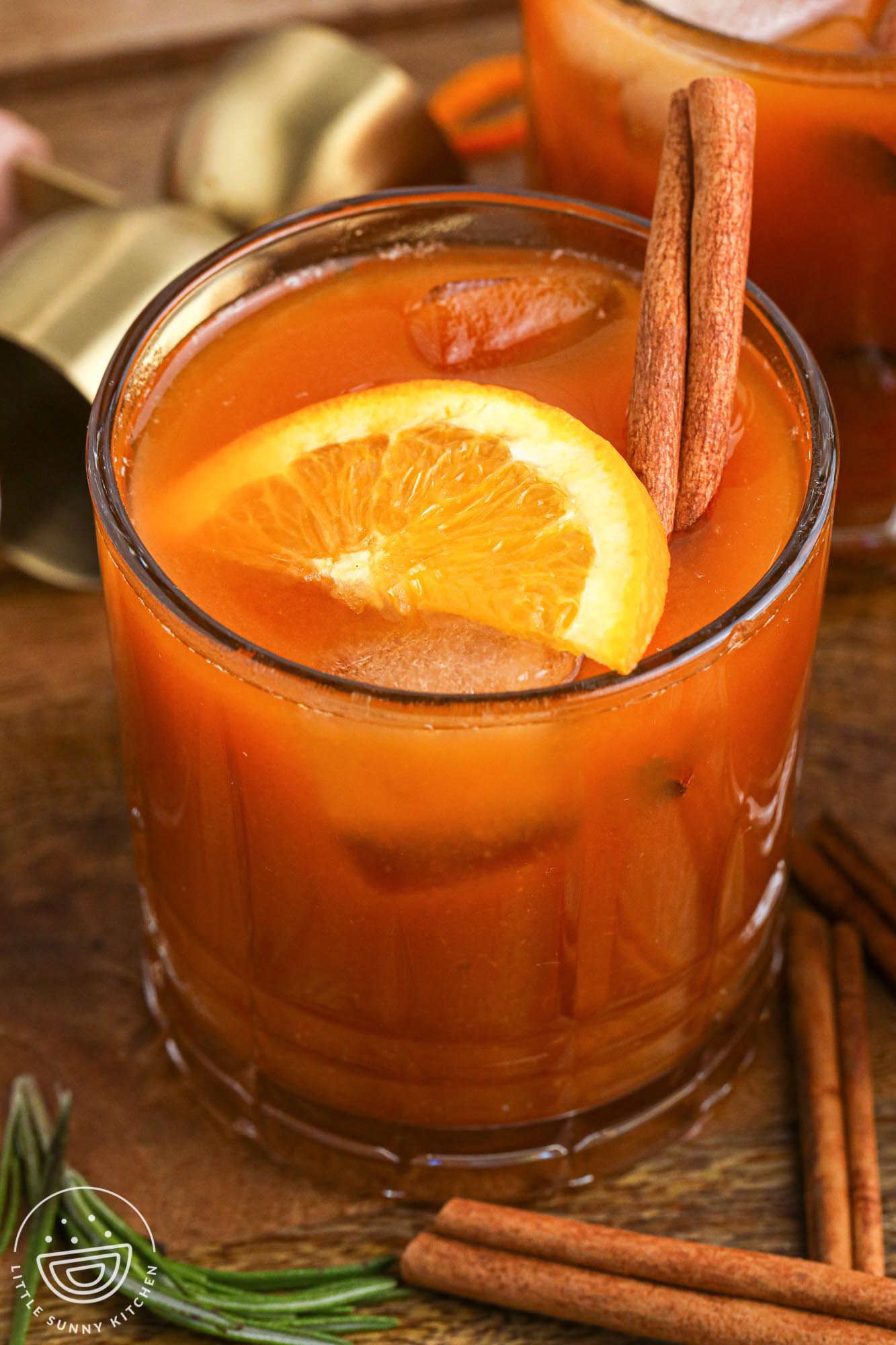 Pumpkin old fashioned cocktail in a glass, with a slice of orange and a cinnamon stick