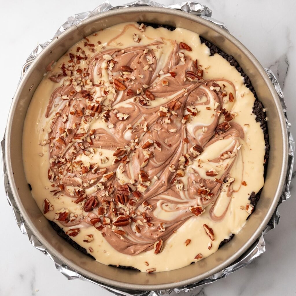 Chocolate and caramel cheesecake filling swirled in a pan, then topped with chopped pecans.