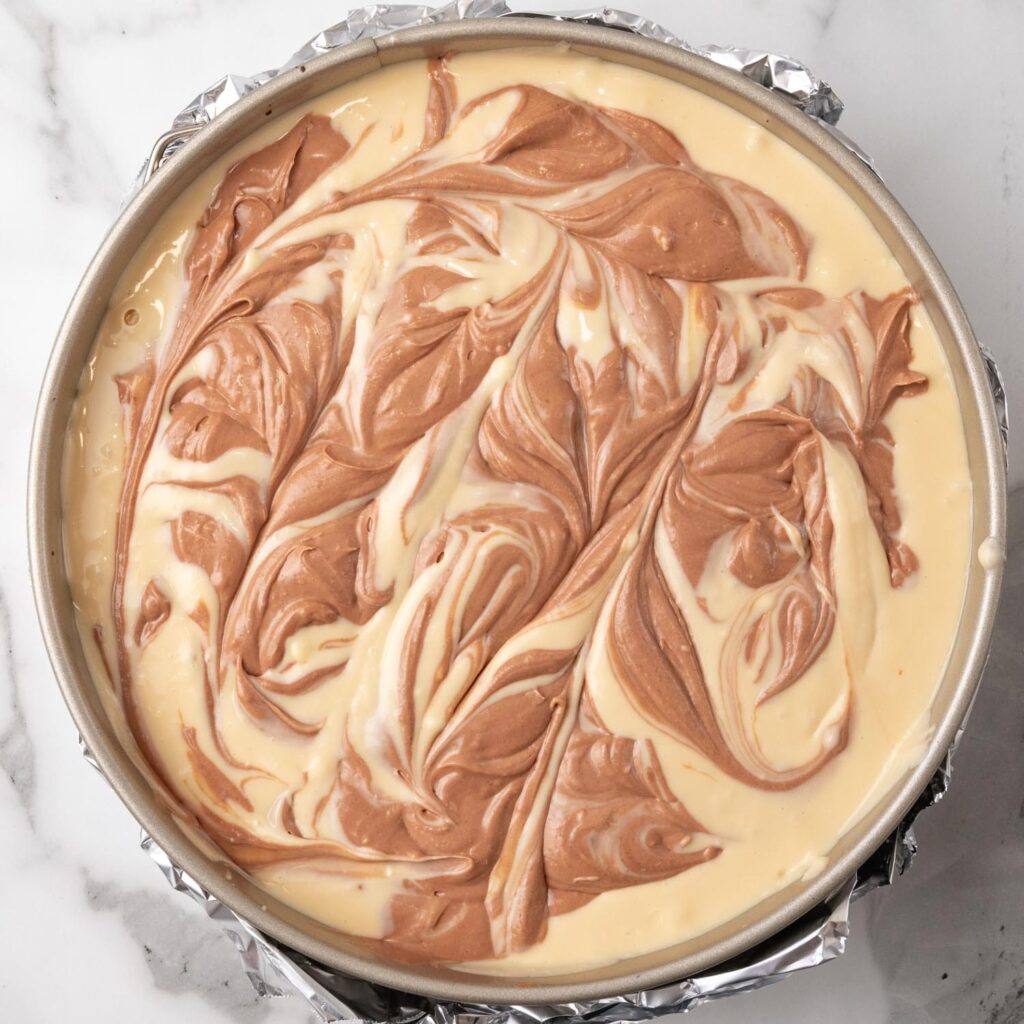 Chocolate and caramel cheesecake filling swirled in a springform pan.