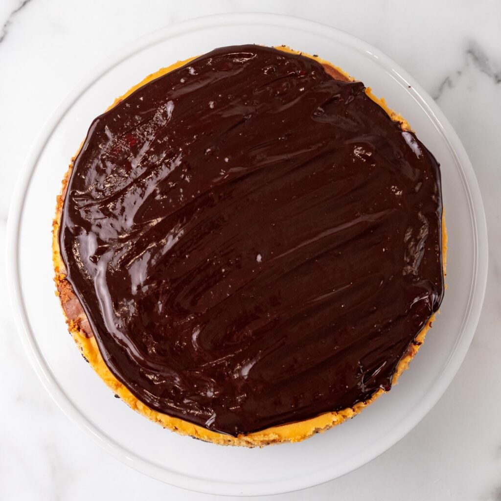 cheesecake on a platter, covered with chocolate ganache.