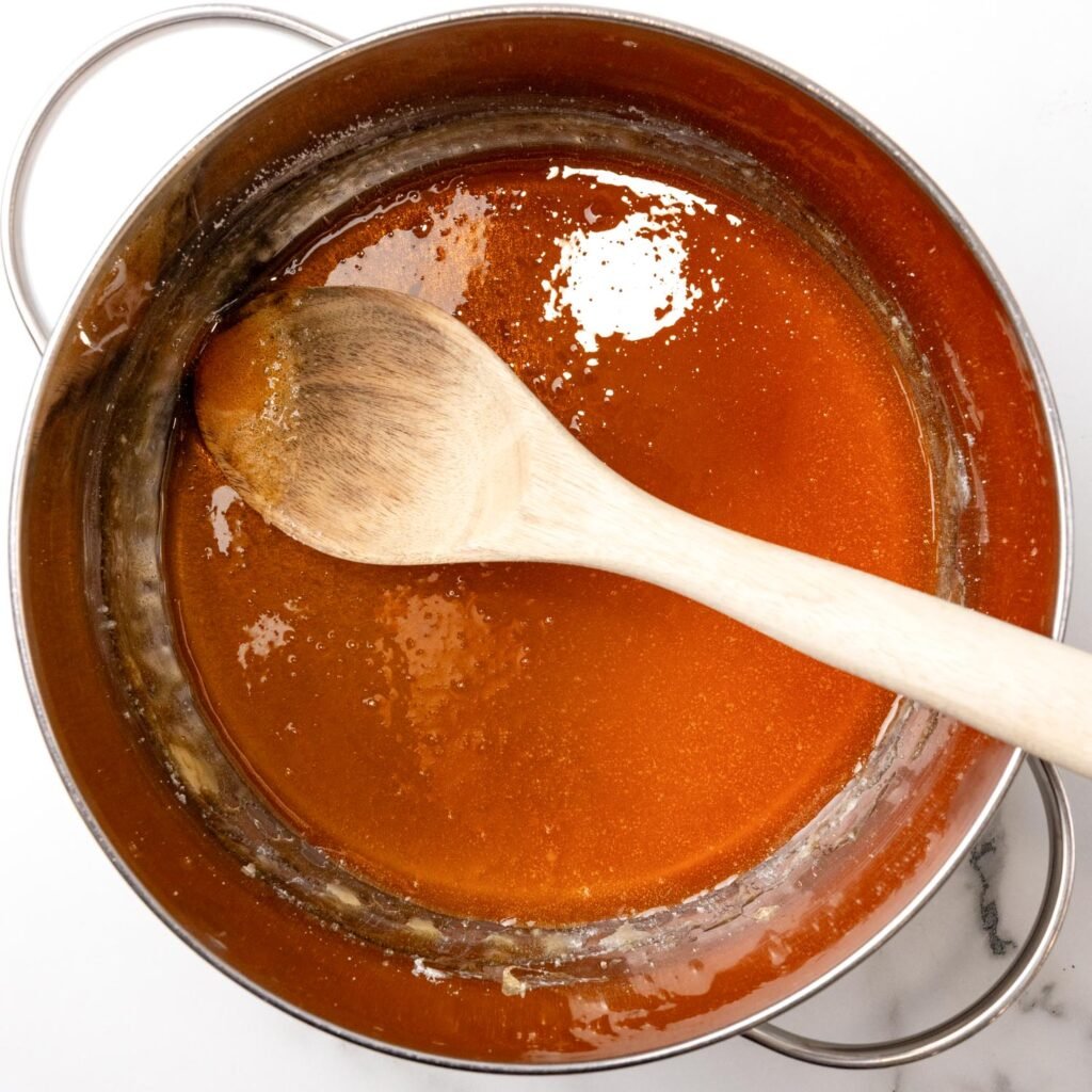 homemade caramel sauce in a saucepan with a wooden spoon.