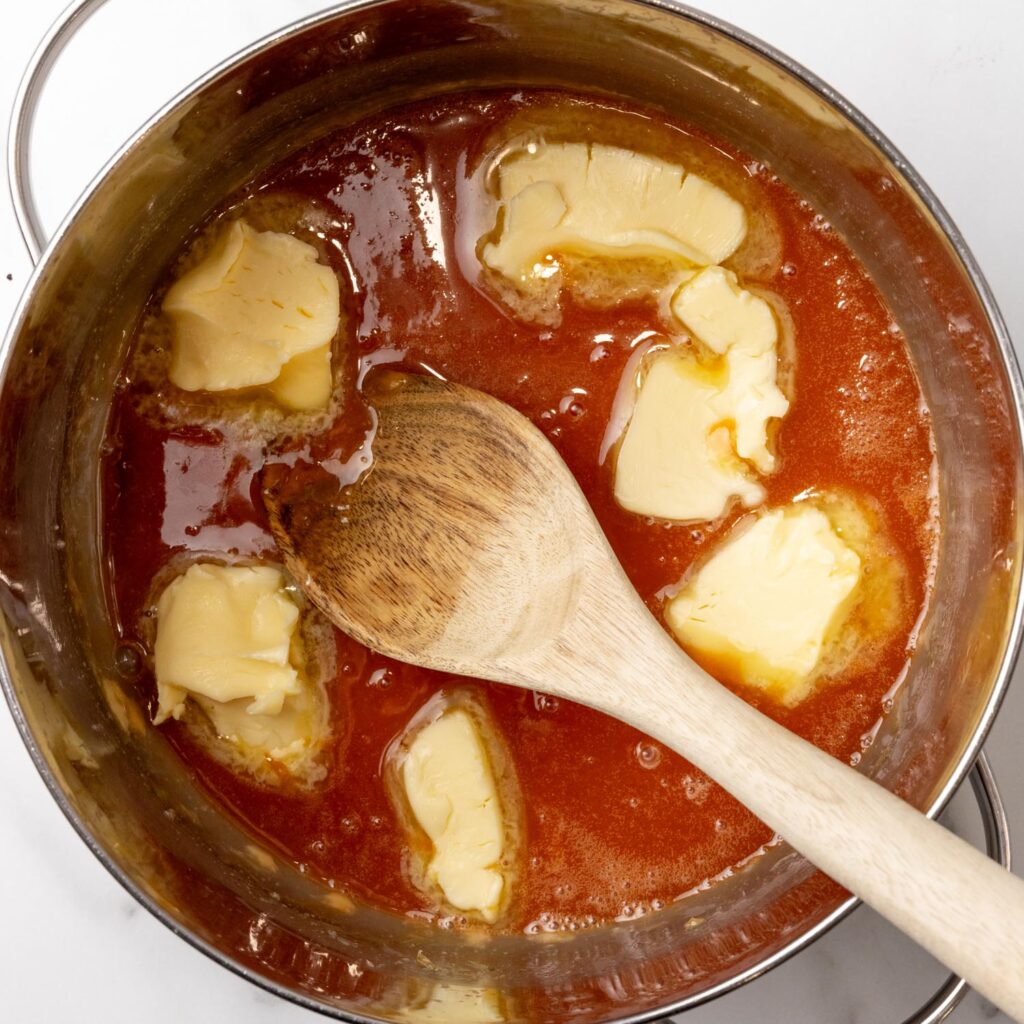 butter added to caramel sauce in a metal saucepan.