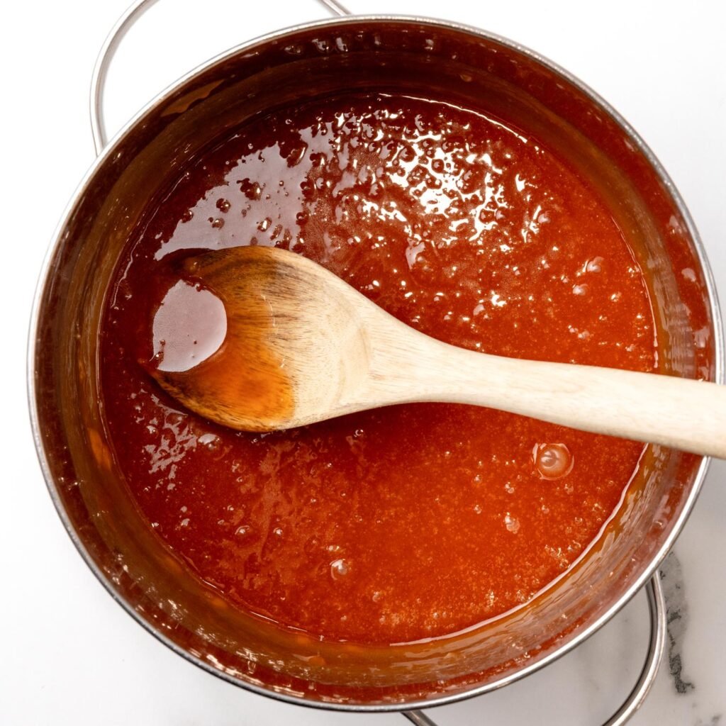 golden brown homemade caramel sauce in a saucepan with a wooden spoon.