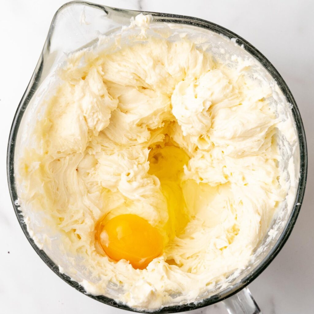 Eggs added to whipped cream cheese mixture in a glass bowl.