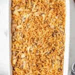 a rectangular white baking dish holding a crispy onion topped casserole of chicken and wild rice.