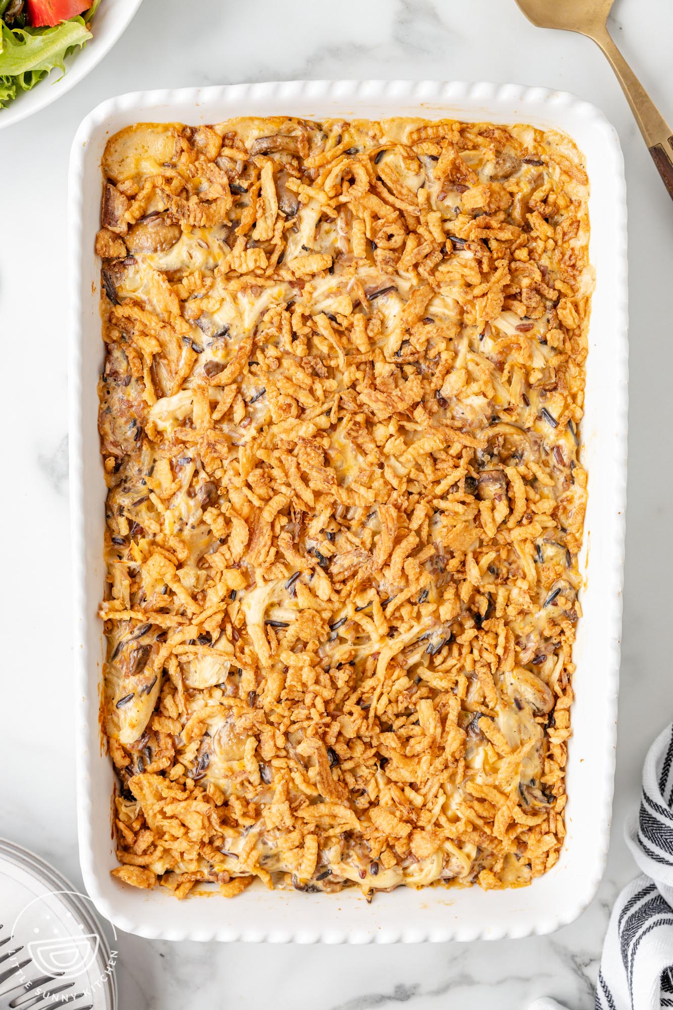 a rectangular white baking dish holding a crispy onion topped casserole of chicken and wild rice.