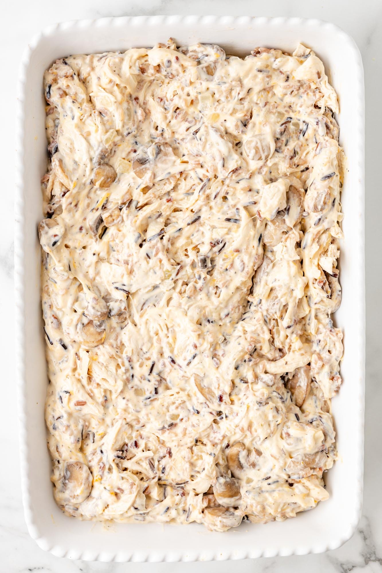 chicken, wild rice, and mushrooms in a creamy sauce, spread into a casserole dish.