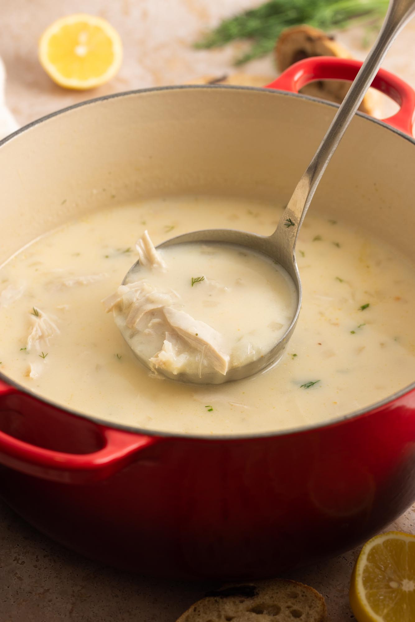 a red dutch oven filled with avgolemono - greek lemon chicken soup.