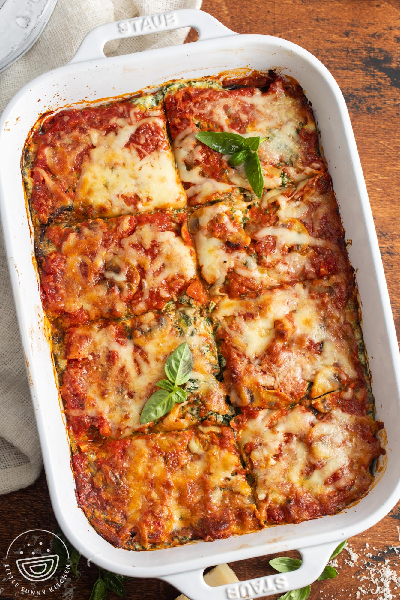 overhead view of homemade eggplant lasagna in a white ceramic baking dish, cut into 8 squares.