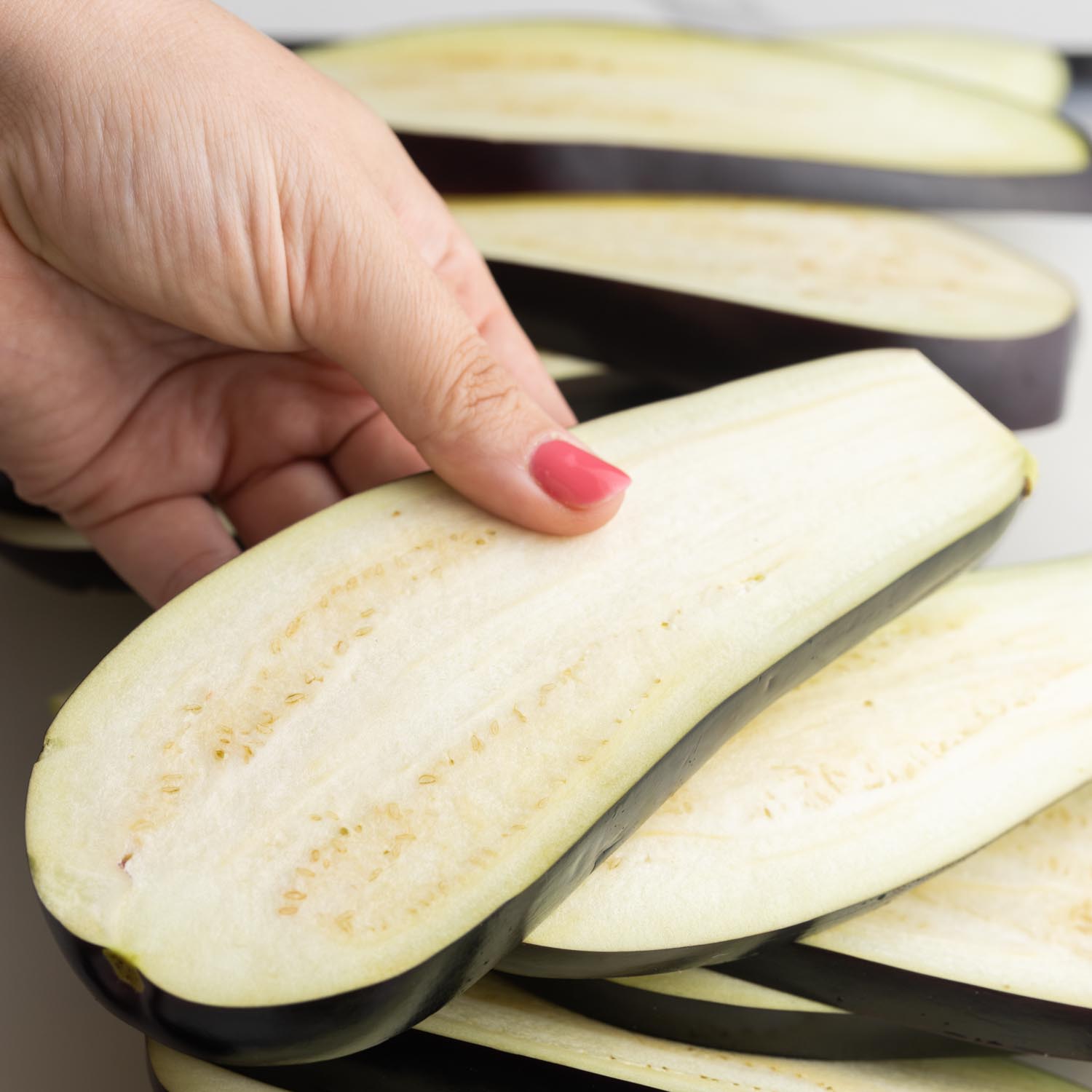 a hand holding slices of eggplant.