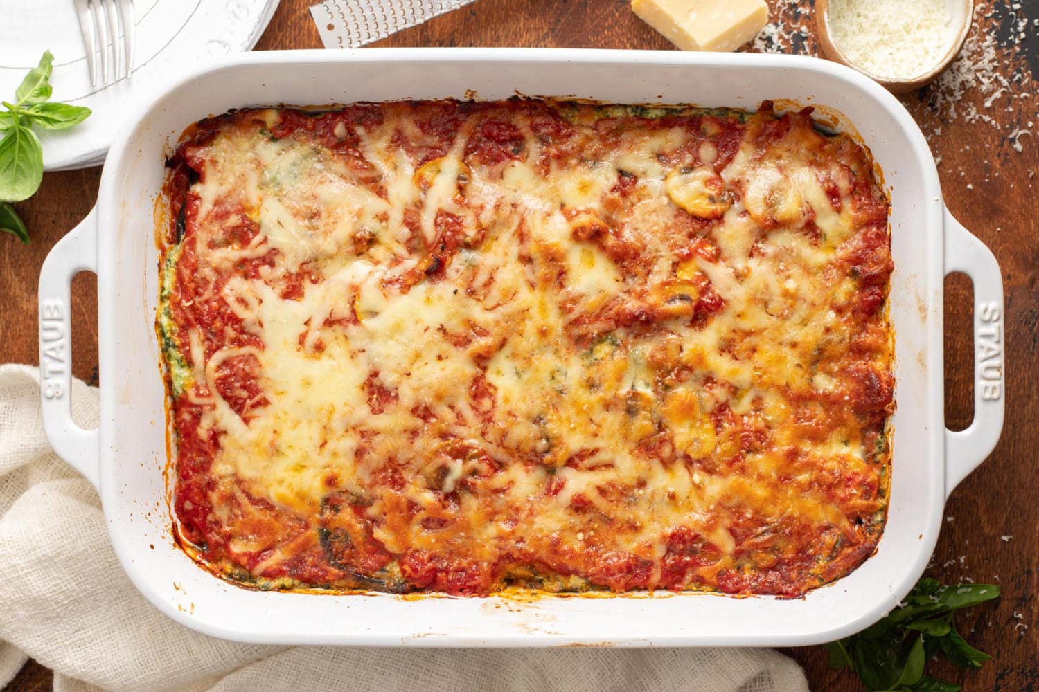 horizontal placement of a 9 by 13 inch baking dish of eggplant lasagna topped with melted cheese and tomato sauce.