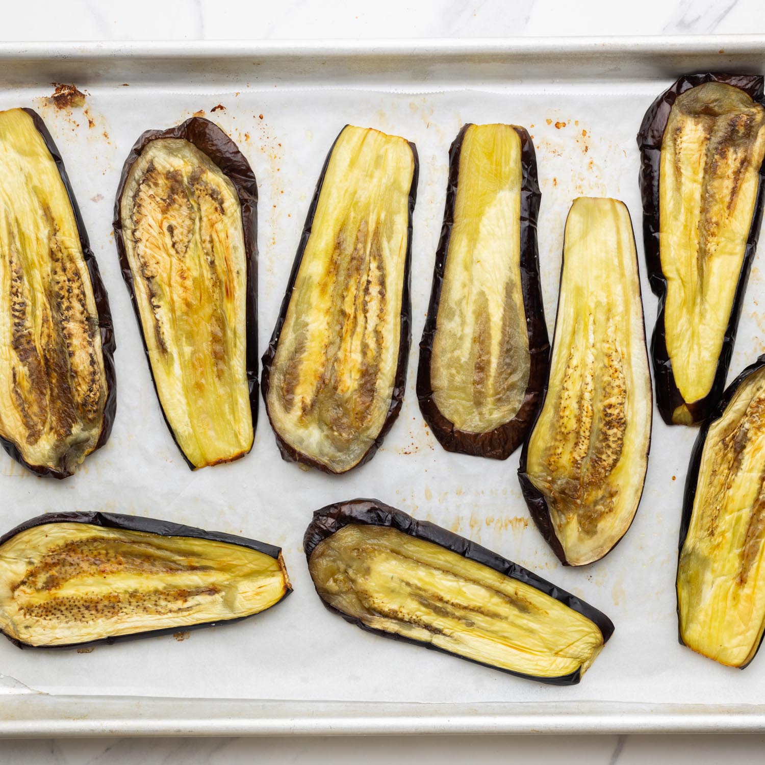 roasted eggplant planks on a parchment lined baking sheet.