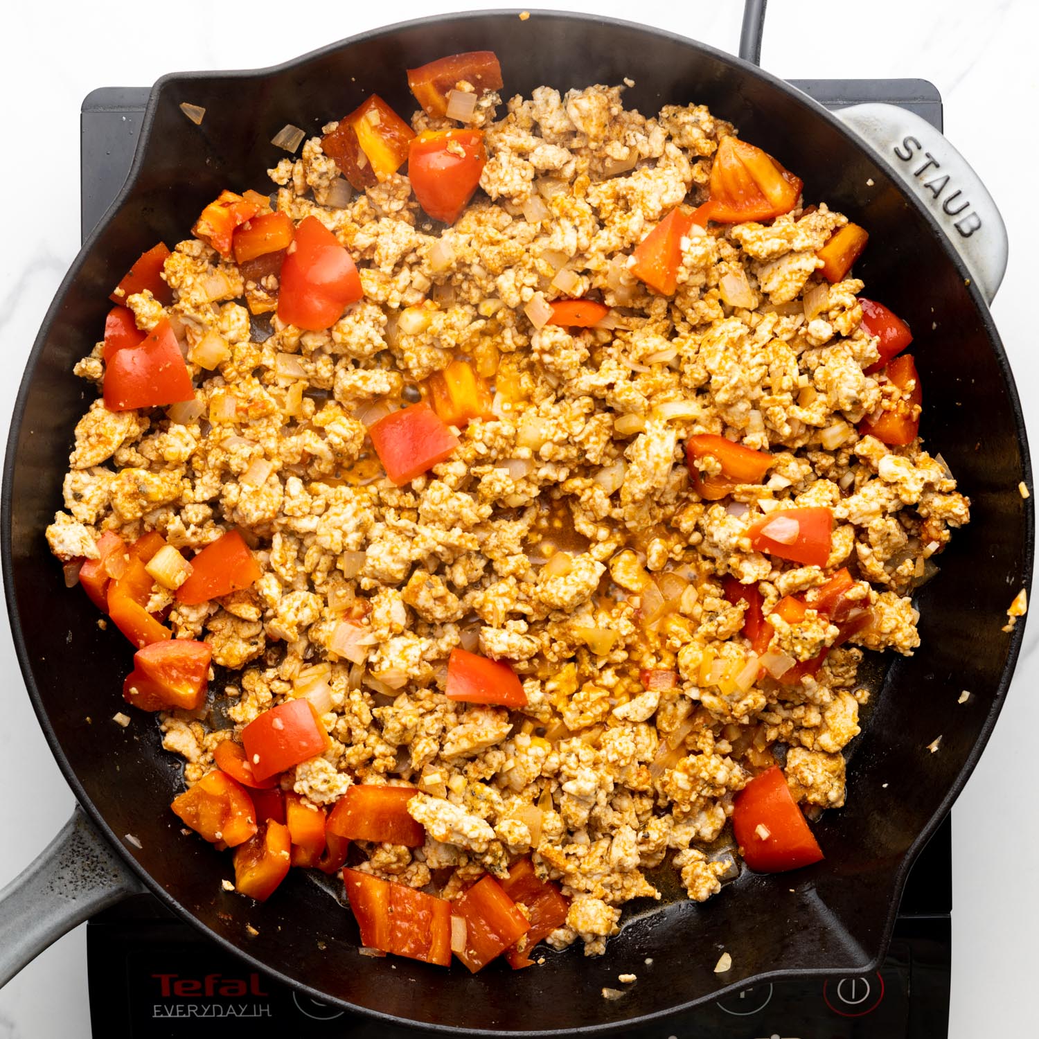 ground turkey, onions, and cubed bell peppers cooked together in a cast iron skillet.