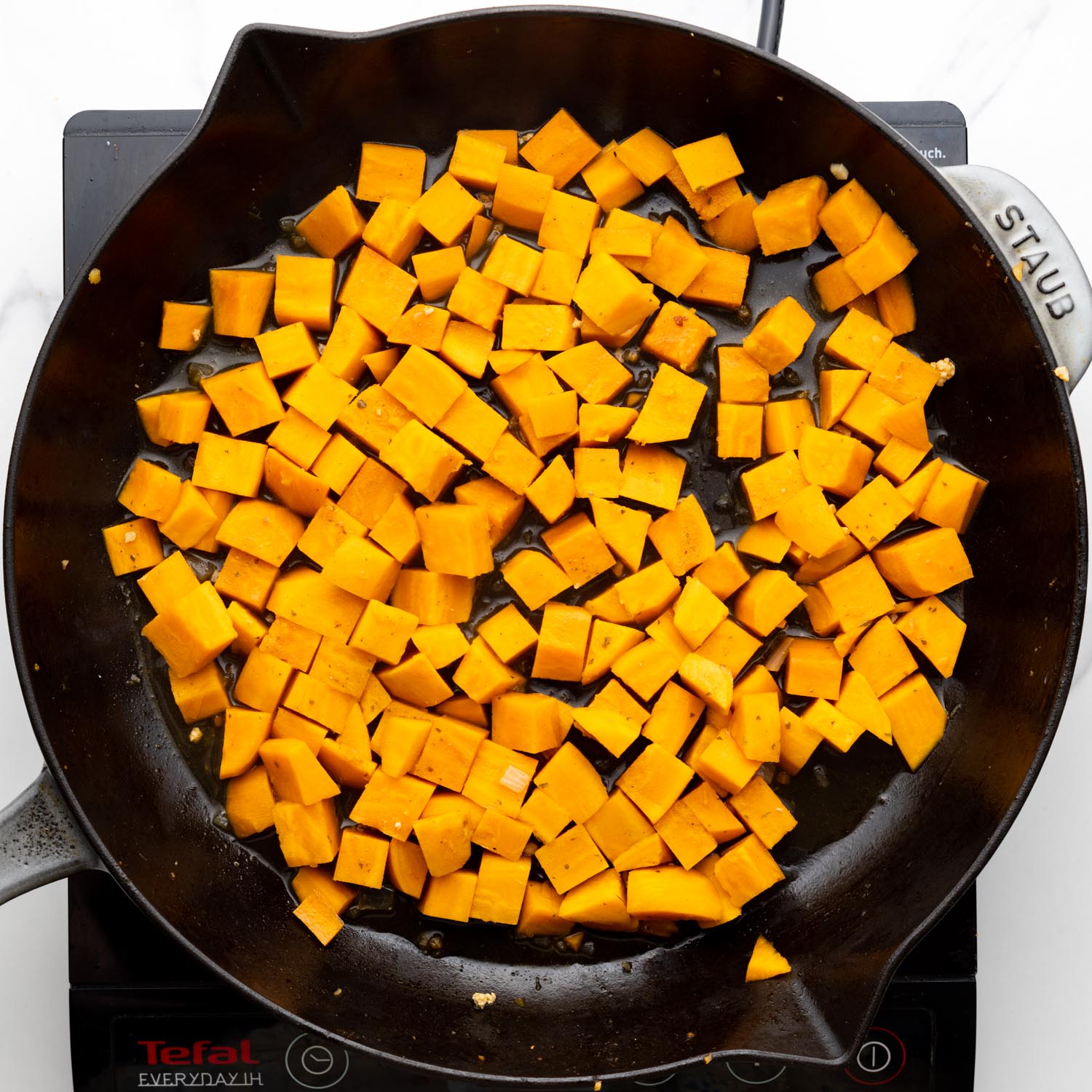 cubed sweet potatoes cooking in a cast iron skillet.