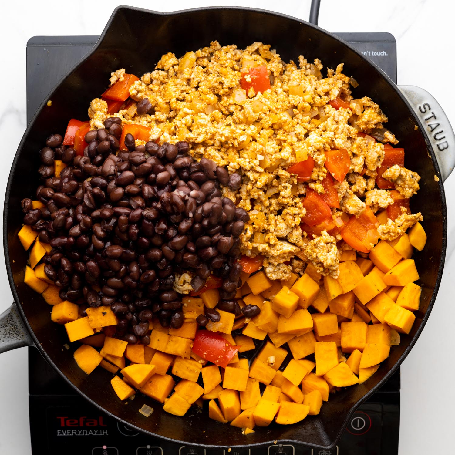 cooked ground turkey, cubed sweet potatoes, and black beans in a cast iron pan.