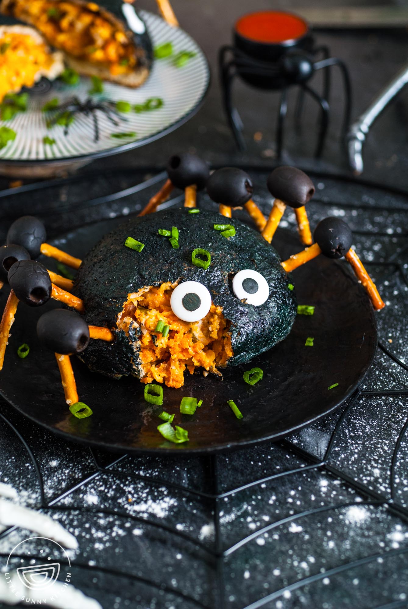 a black buffalo chicken stuffed pizza bomb with pretzel legs and eyes to look like a spider. A bite is taken from the front of the face.