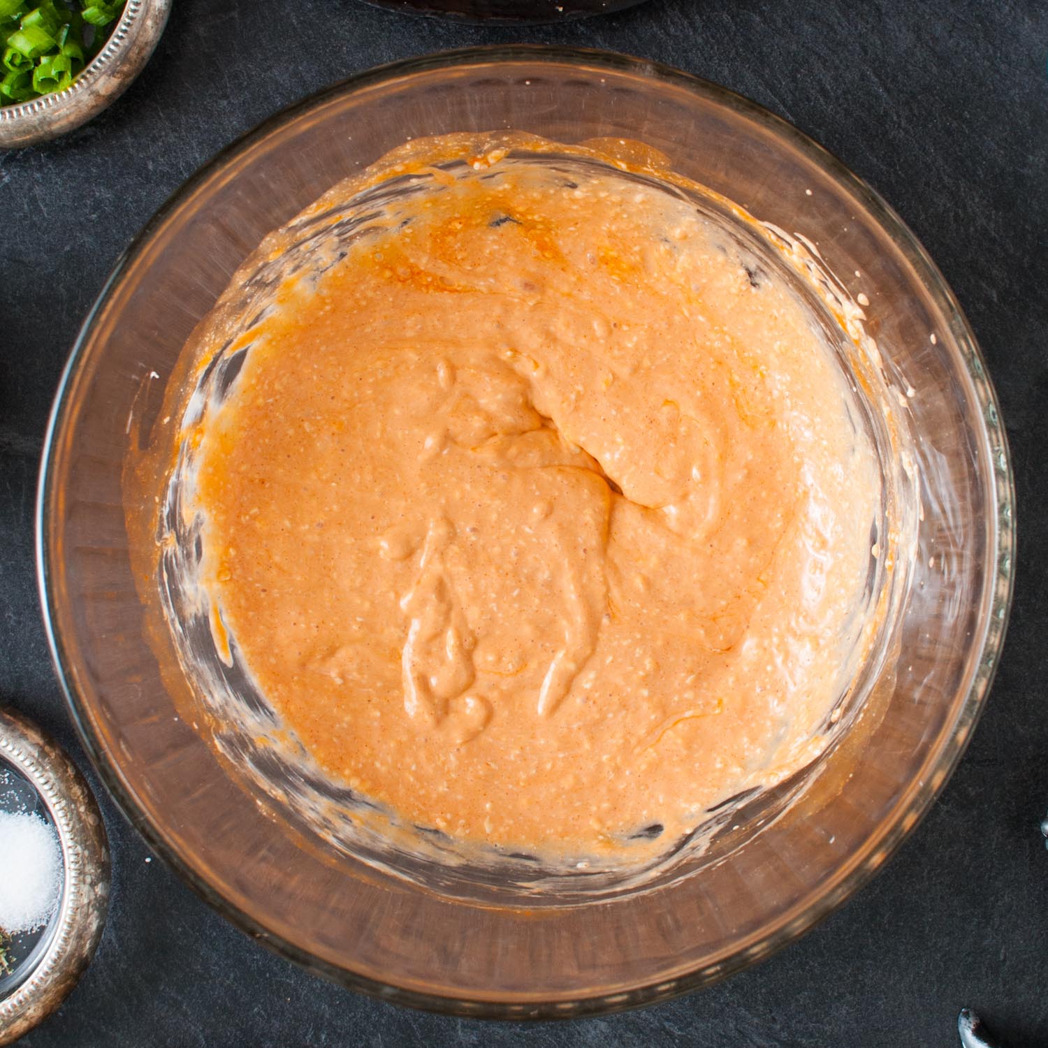 cream cheese mixed with buffalo wing sauce in a glass bowl.