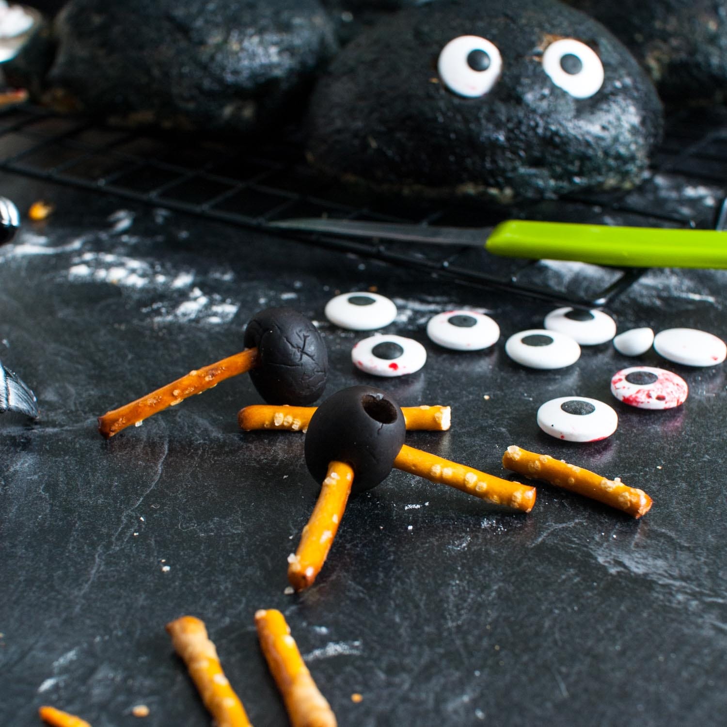 spider legs being made with pretzel sticks and black olives.