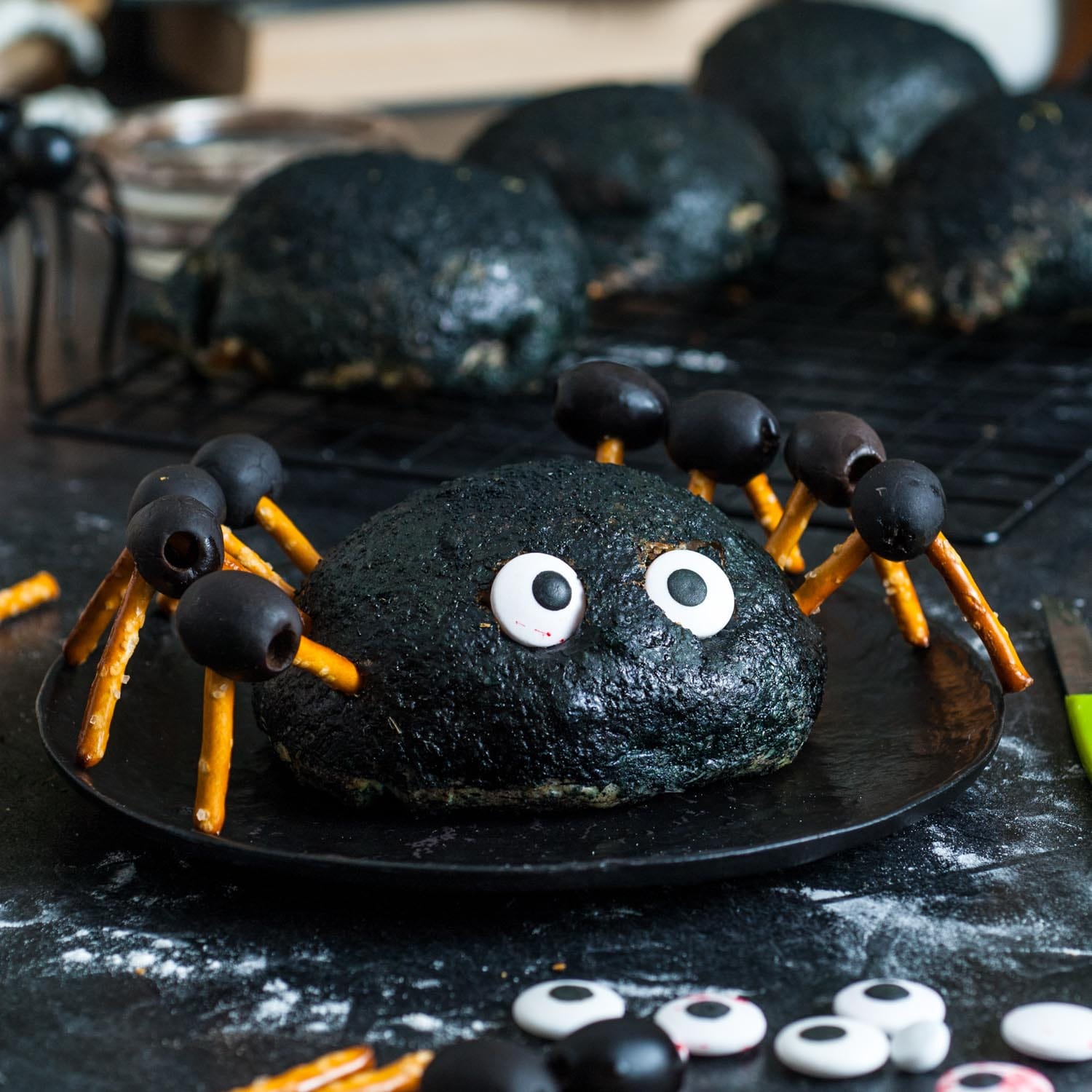 a buffalo chicken bomb which is buffalo chicken and cheese inside a pizza dough ball, decorated black and with pretzel and olive leggs to look like a large spider.