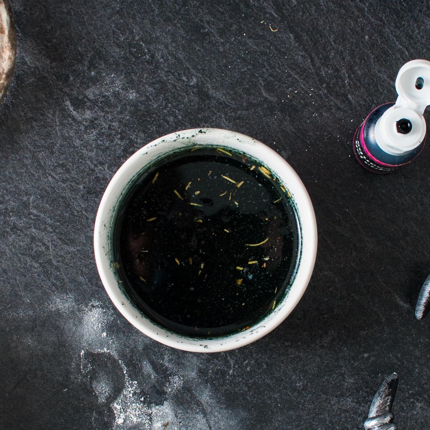 black food coloring added to garlic herb butter in a white ramekin.