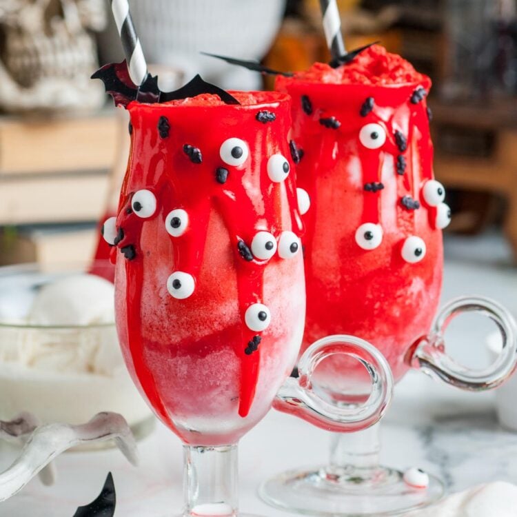 Two Halloween vampire floats decorated with red icing, candy eyes, black striped straws, and small bats.