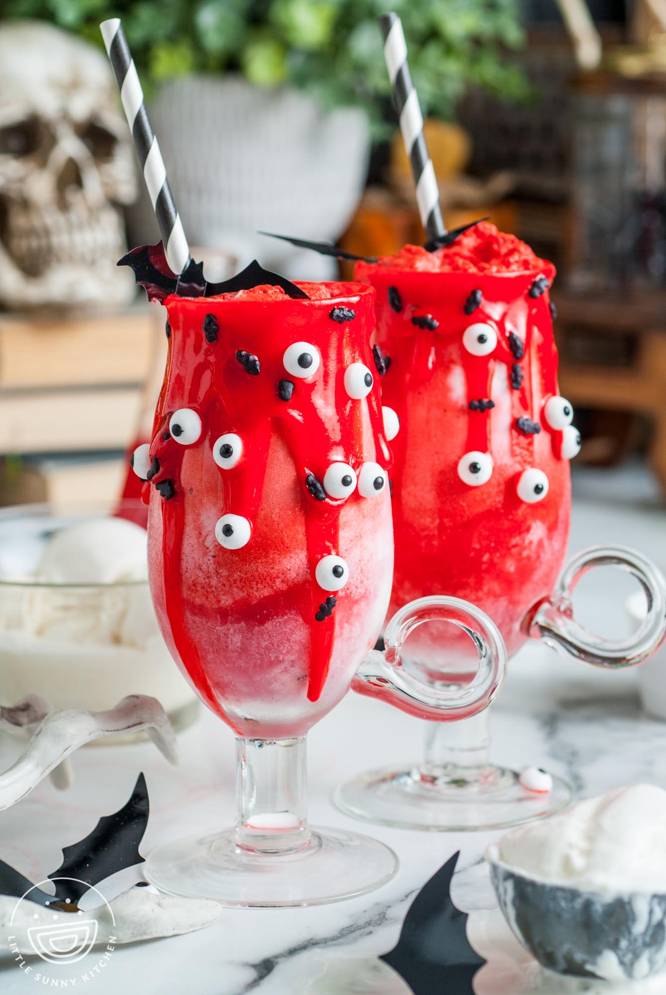 Two Halloween vampire floats decorated with red icing, candy eyes, black striped straws, and small bats.