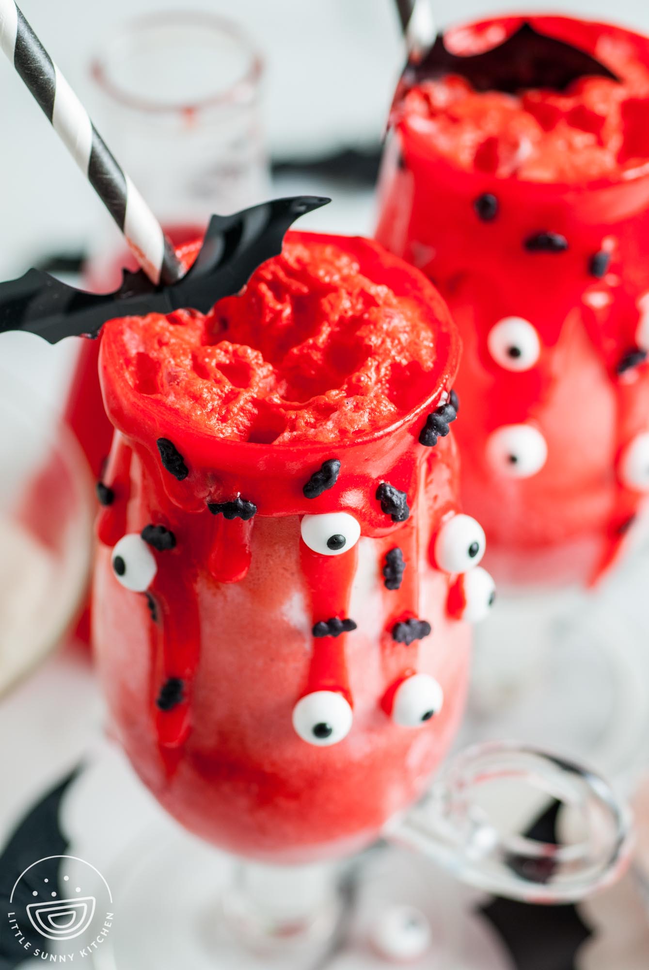 ice cream floats made with red food coloring and fruit punch soda, decorated with red icing, candy eyes, bat sprinkles.