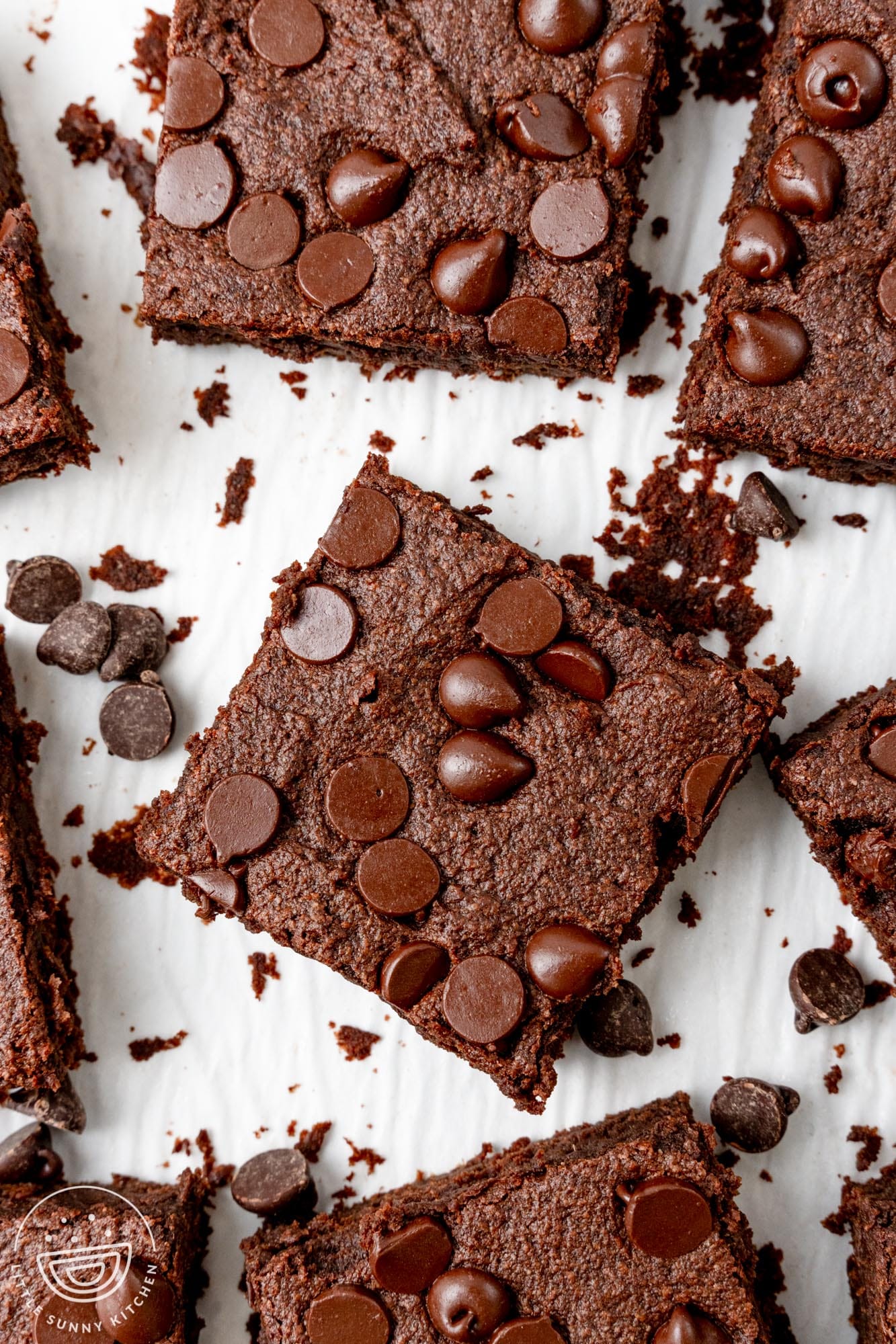 square cut brownies made with sweet potatoes on parchment paper. The brownies are topped with chocolate chips.