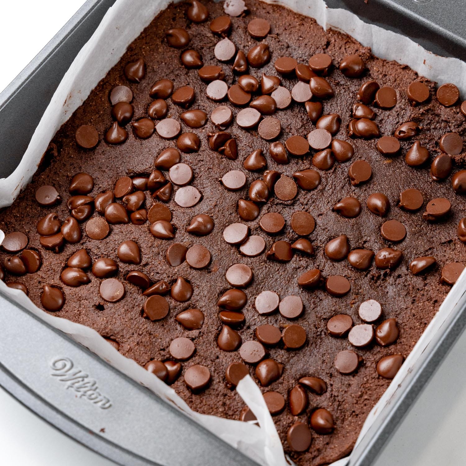 a pan of baked sweet potato brownies topped with partially melted chocolate chips