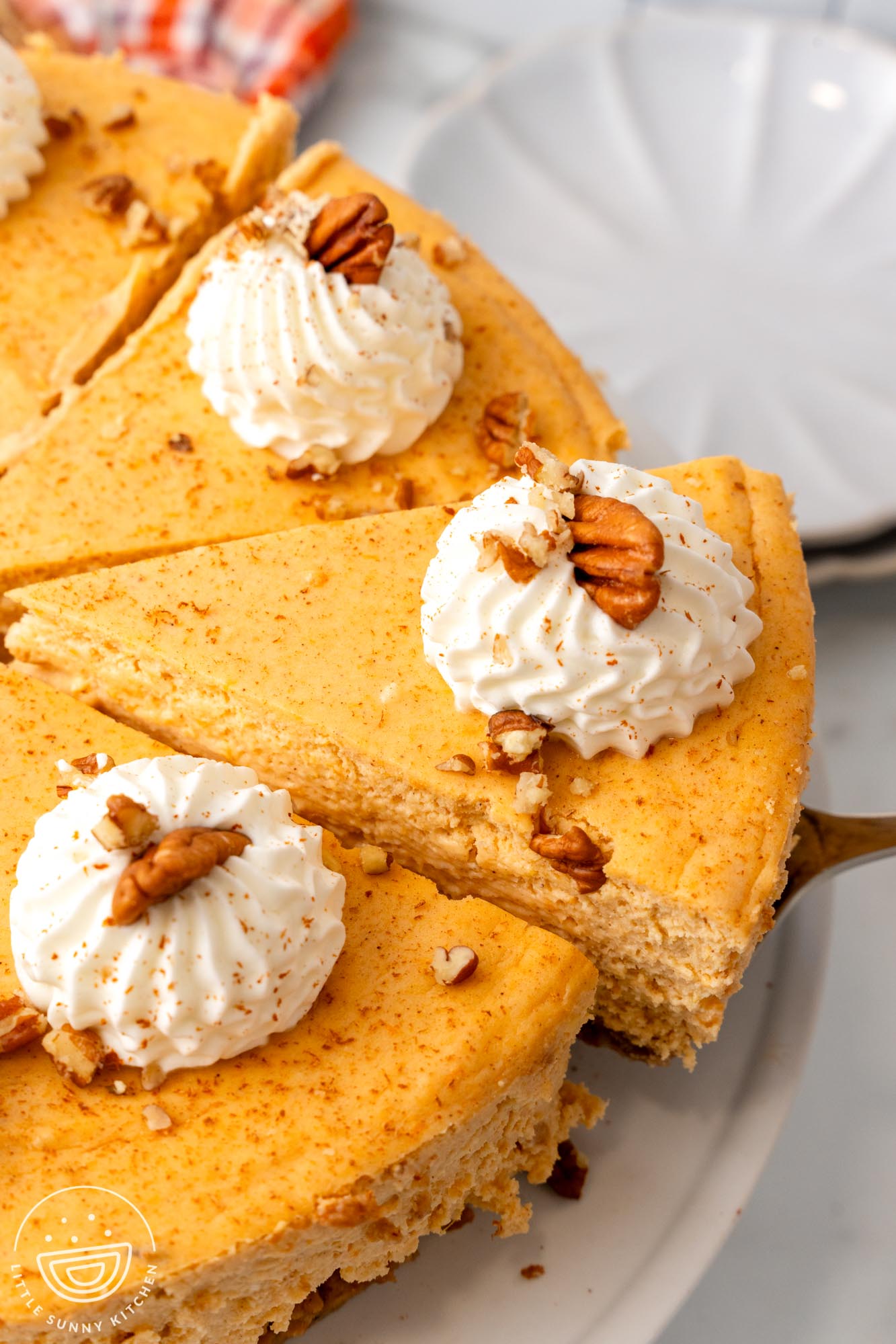 a whole sweet potato cheesecake cut into wedges. Half of the cake is visible in the photo, and one slice is removed with a cake server.