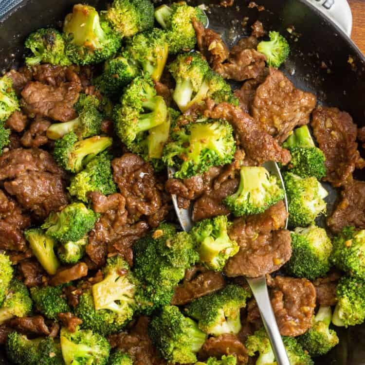 a large cast iron pan filled with tender sliced beef and stir fried broccoli.