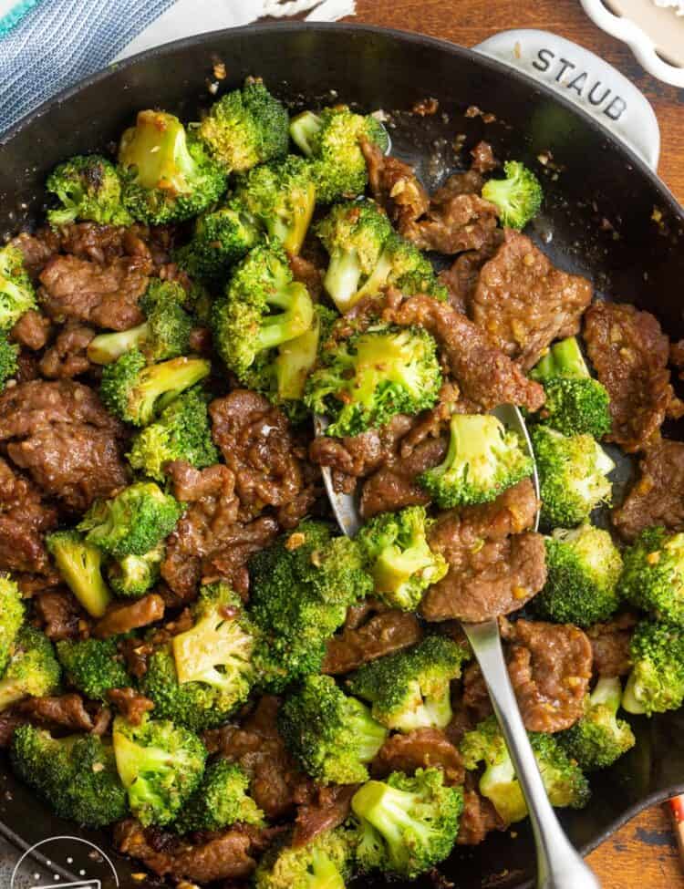 a large cast iron pan filled with tender sliced beef and stir fried broccoli.