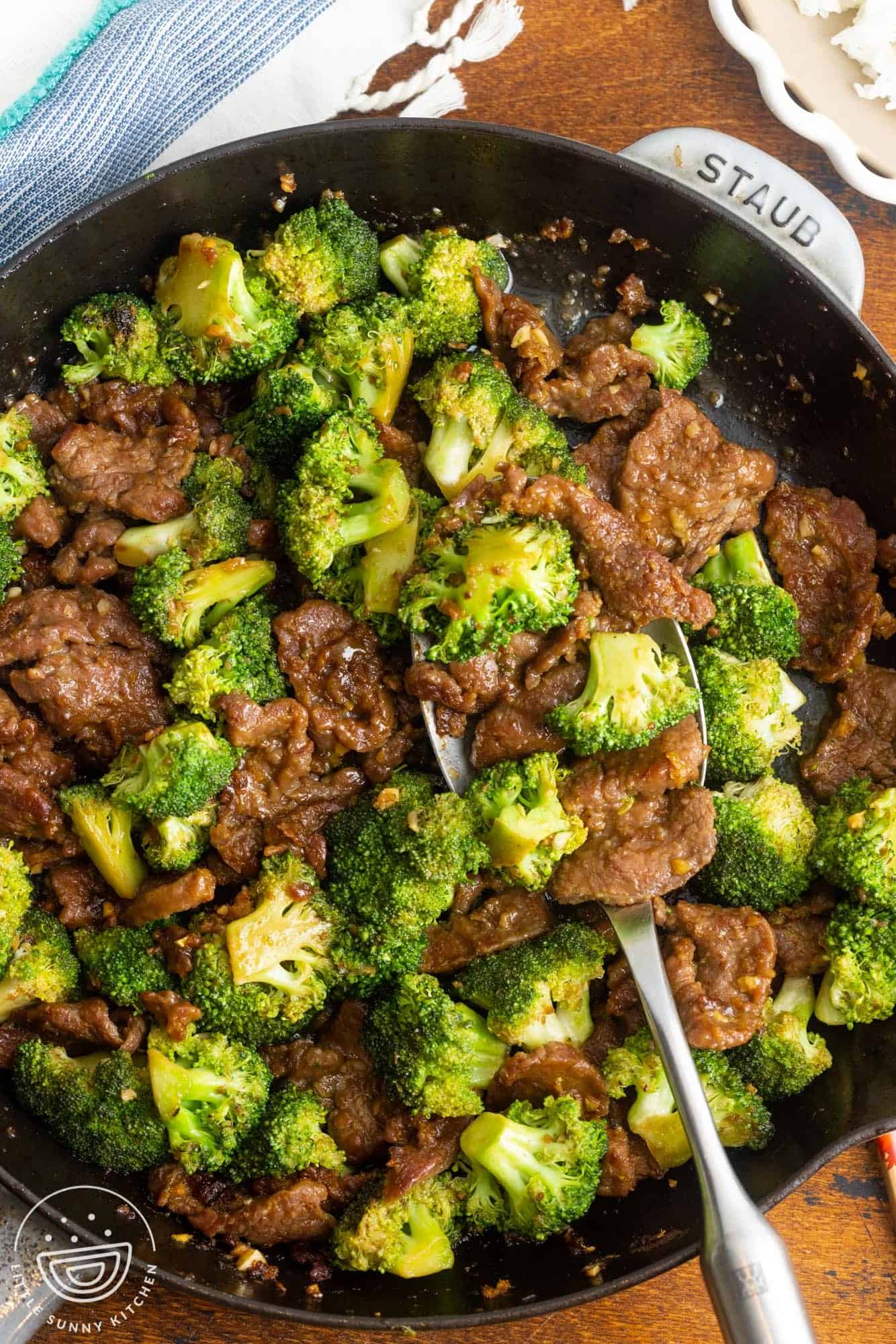 a large cast iron pan filled with tender sliced beef and stir fried broccoli.